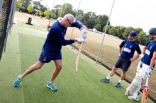 Phil playing cricket, holding a bat in a navy outfit.